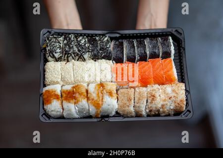 Sushi und Brötchen zu Hause zubereiten. Sushi mit Meeresfrüchten, Salat und weißem Reis. Essen für Familie und Freunde. Eine Reihe verschiedener Brötchen und Sushi auf einem Tablett Stockfoto