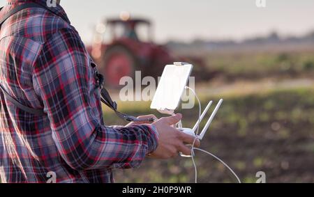 Nahaufnahme der Fernbedienung mit Tablet für Drohne in den Händen des Bauern auf dem Feld. Hightech-Innovationen zur Steigerung der Produktivität in der Landwirtschaft Stockfoto