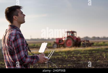 Attraktiver Landwirt, der Drohne über Ackerland steuert. Hightech-Innovationen zur Steigerung der Produktivität in der Landwirtschaft Stockfoto