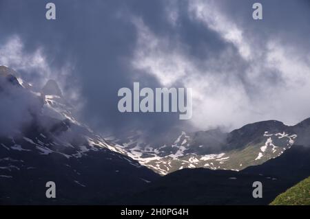 Niedrige dunkle Wolken über Bergen mit Schnee in der Sonne am Anfang, Grindelwald, Schweiz Stockfoto