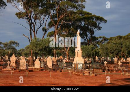 Kalgoorlie Friedhof mit roter Erde, Grabsteinen, Bäumen und dunklen Wolken kurz nach einem Gewitter in Kalgoorlie, Westaustralien Stockfoto