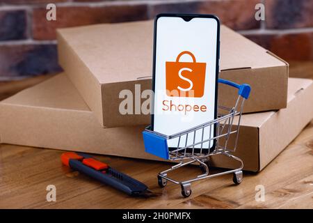 Shopee ist ein E-Commerce-Technologieunternehmen. Smartphone mit Shopee-Logo auf dem Bildschirm, Warenkorb und Paketen. Stockfoto