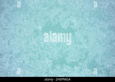Jahre mit einem grünlich-grauen Farbton, strukturiert mit weißem Frost und einem gemusterten Eismuster. Hintergrund. Stockfoto