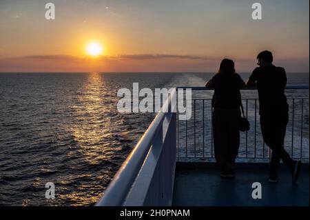Sonnenuntergang über dem Mittelmeer von der Fähre zwischen Toulon und Korsika aus gesehen. Paar auf dem Deck mit Ellbogen auf der Leitplanke und Blick Stockfoto