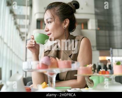 Reife asiatische Frau genießt Nachmittagstee im modernen Hotelrestaurant Stockfoto