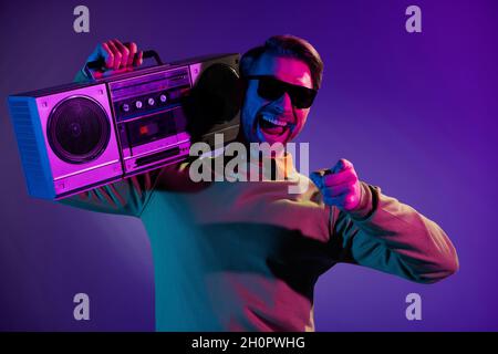 Foto von jungen aufgeregt Mann glücklich positive Lächeln boombox Disco Nachtleben isoliert über neonfarbenen Hintergrund Stockfoto