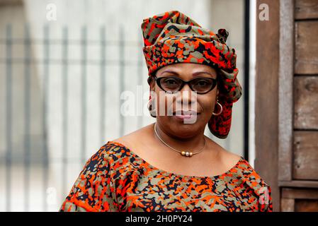 Charmante afrikanische Frau in einer Brille, die im Freien steht und lächelnd auf die Kamera schaut. Stockfoto