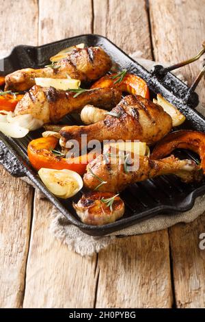 Gegrillte Hähnchenschenkel mit saisonalem Gemüse aus der Nähe in einer Grillpfanne auf dem Tisch. Vertikal Stockfoto