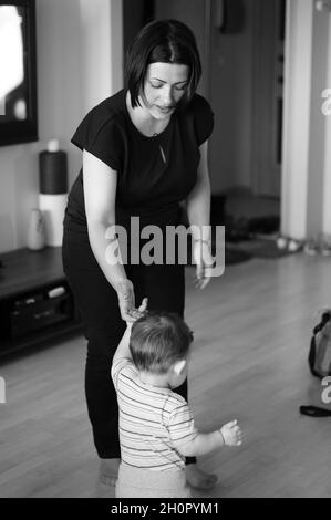 Graustufenaufnahme einer jungen Mutter mit ihrem Jungen zu Hause Stockfoto
