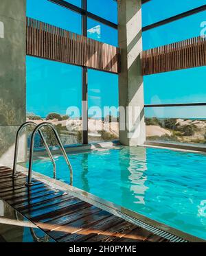 Schönes Hallenbad im Luxus-Spa-Hotel oder Ferienvilla am Meer an sonnigen Tagen, Strandhaus mit Panoramafenstern und Meerblick Stockfoto