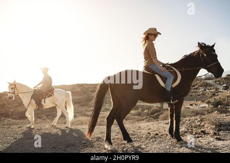 Junges Paar Reiten Pferde tun Ausflug auf dem Land während Sonnenuntergang Zeit - Fokus auf Frau Stockfoto