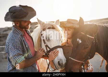 Bauernpaar Spaß mit gebissenen Pferden während sonnigen Tages in Ranch Corral - Fokus auf Zentrum Tierauge Stockfoto