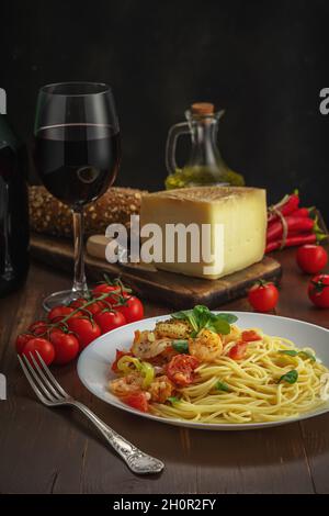 Spaghetti mit Garnelen, Kirschtomaten und Gewürzen auf Holzhintergrund. Hintergrund für das Essen. Stockfoto
