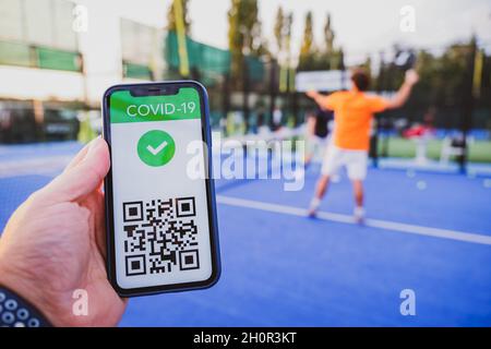 Mann zeigt Impfpass covid-19 mit App auf Smartphone erster Sport zu tun, Coronavirus Konzept Stockfoto