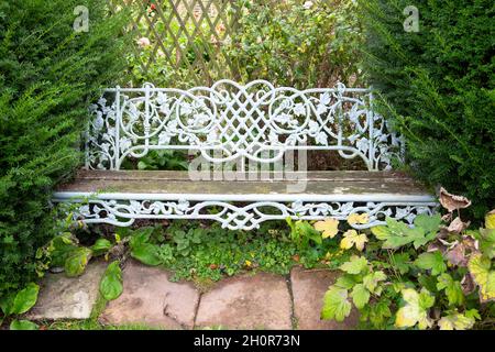 Kunstvolle alte alte alte Gartenbank aus Eisen und Holz mit Eibenbäumen auf beiden Seiten in Rye East Sussex England Großbritannien Großbritannien KATHY DEWITT Stockfoto