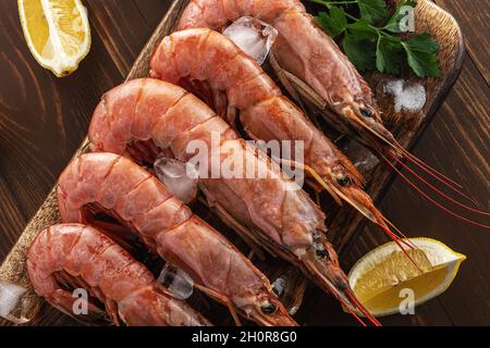 Frische Garnelen auf Holzboden mit Zitronenscheibe. Meeresfrüchte Hintergrund. Stockfoto