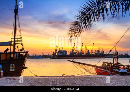 Blick auf den Hafen von Varna bei Sonnenuntergang, Segelschiffe und Hafenkrane im Hintergrund, an der Schwarzmeerküste Bulgariens Stockfoto