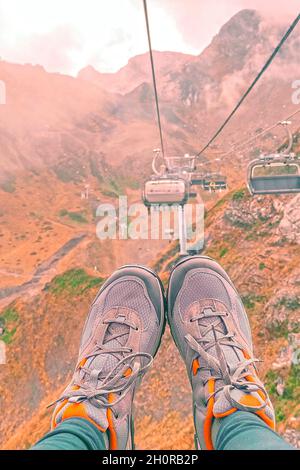 In der Nähe der weiblichen Beine in Turnschuhen in die Berge mit der Seilbahn Stockfoto