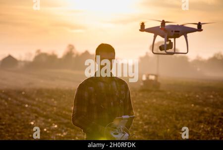 Attraktiver Landwirt, der Drohne über Ackerland steuert. Hightech-Innovationen zur Steigerung der Produktivität in der Landwirtschaft Stockfoto