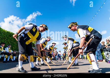 Blick aus der tiefen Perspektive auf zwei Reihen von Männern von Wantsum Morris, die beim Broadstairs Folk Week Festival mit Holzstäben in ihren Händen tanzen. Blauer Himmel. Stockfoto