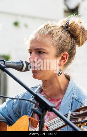 Nahaufnahme des Gesichts von Mimi O'Halloran, einer jungen Singer-Songwriterin, die bei einem Open-Air-Konzert bei einer Veranstaltung in ein Mikophon singt. Stockfoto