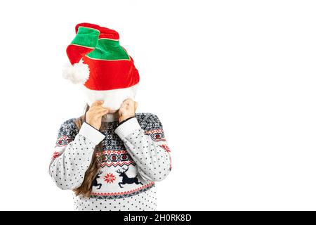 Kind in weiß gestrickter Weihnachts-Pullover mit Rentier-Fell-Gesicht unter Zwerghut, isoliert auf weißem Hintergrund Stockfoto