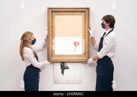 Aktenfoto vom 03/09/21 von Kunsthändlern in Sothebys Auktionshaus mit Banksy's 'Love is in the bin', das sich sofort selbst zerkleinert hat, nachdem es bei einer Auktion für £1,042,000 verkauft wurde, bevor es heute Abend bei Sotheby's, London, zur Auktion zurückkehrt, mit einer Schätzung, die zwischen £4 und £6 Millionen einbringt. Ausgabedatum: Donnerstag, 14. Oktober 2021. Stockfoto