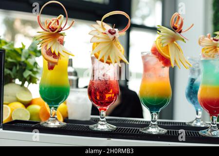 Cocktailbar, mehrfarbig dekorierte Cocktailgläser, Urlaubskonzept, alkoholische Getränke, Foto aus nächster Nähe. Zitrusfrüchte im Hintergrund. Stockfoto