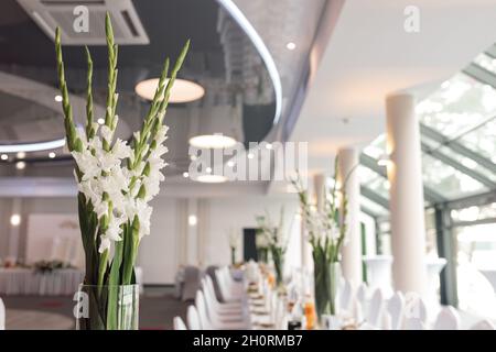 Festkonzept gedeckte Tische in der Lobby des Restaurants oder Hotels warten auf die Gäste. Tischdecken. Keine Personen. Glasfenster Stockfoto