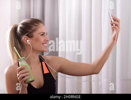 Junge ziemlich sportliche Mädchen unter Selfie mit grünen Smoothie im Glas Stockfoto