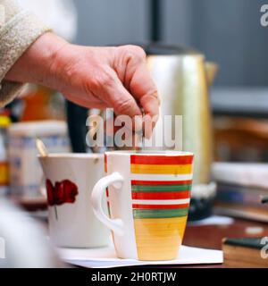 Eine Frau rührt Zucker mit einem Teelöffel in einer Tasse Tee Stockfoto