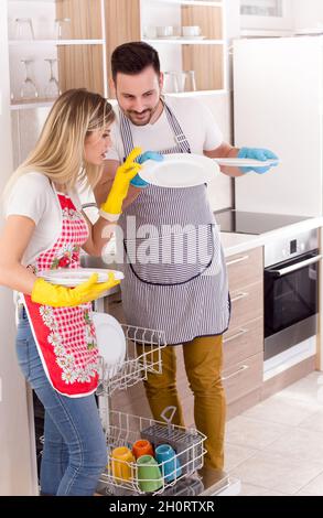 Junges Paar, das die Sauberkeit der Teller von der Spülmaschine überprüft Stockfoto