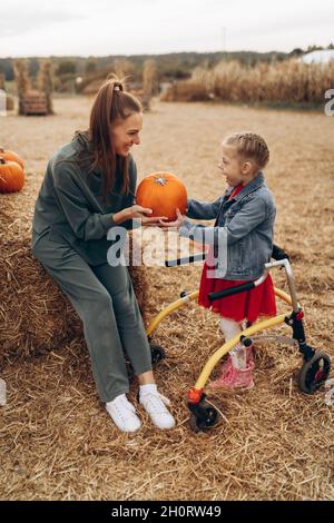 Mutter und ihre behinderte Tochter verbringen Zeit auf einem Kürbisfeld. Stockfoto