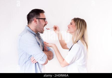 Männliche Patientin, die einen Löffel voll mit verschiedenen Pillen vom weiblichen Arzt abweist Stockfoto