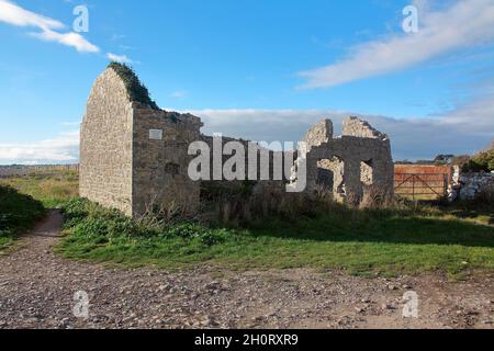 Ein altes, aus Stein erbautes Gebäude, das jetzt in einem Zustand des Zerfalles und langsam zerbröckelt, auf dem Parkplatz in Limpert am Meer. Stockfoto