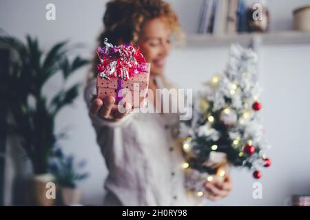 Nahaufnahme des weihnachtsgeschenks und entkokselte glückliche Frau, die während der Weihnachtsfeiertage Baum und Dekoration zu Hause hält. Konzept des Geschenks ohne Stockfoto
