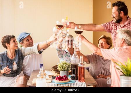 Fröhliche Gruppe von Menschen haben Spaß zusammen genießen und feiern mit Wein und Alkohol - ältere und Erwachsene Paare und Familie zu Mittag essen und l Stockfoto