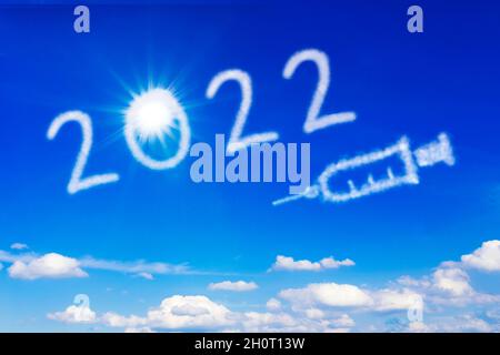 Happy New Year Konzept. Helle Sonne, Nummer 2022 und ein Spritzensymbol am blauen Himmel, das ein Ende der covid Pandemie symbolisiert. Stockfoto