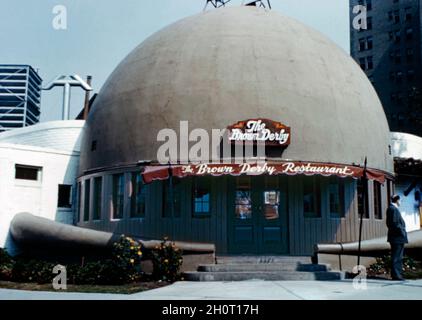 Das ursprüngliche Brown Derby Restaurant in 3427 Wilshire Boulevard, Los Angeles, Kalifornien, USA in den 1950er Jahren. Der erste und bekannteste einer späteren Restaurantkette war wie ein Derby-Hut eines Mannes geformt, ein ikonisches Bild, das zum Synonym für das Goldene Zeitalter Hollywoods wurde. Es wurde 1926 von Wilson Mizner eröffnet. Die Restaurants schlossen in den 1980er Jahren, aber ein von Disney unterstütztes nationales Franchising-Programm von Brown Derby belebte die Marke im 21. Jahrhundert – ein altes Foto aus den 1950er Jahren. Stockfoto