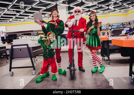 In voller Länge Körpergröße Ansicht von attraktiven funky fröhliche Freunde Elfen Wahl Kauf Geschenke festal Adventszeit im Einkaufszentrum im Innenbereich Stockfoto