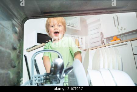 Kleinkinder nehmen Geschirr aus der Spülmaschine in der Küche Stockfoto