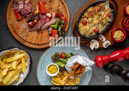 Antipasti, Hühnerfilet und Auflaufpilze auf dem Steintisch Stockfoto