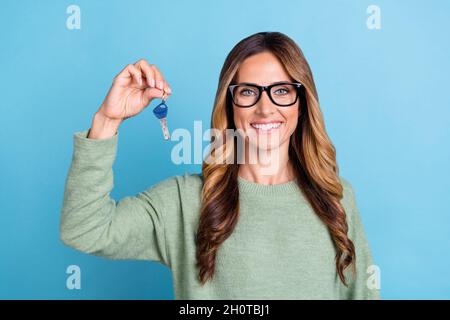 Foto Porträt Frau trägt Brille lächelnd Keeping Schlüssel von neuem Haus isoliert pastellblau Hintergrund Stockfoto