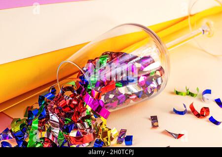 Weinglas voller farbenfroher Konfetti auf hellem Hintergrund. Geburtstag und Jubiläumsfeier, Neujahr und Weihnachten Gratulation concep Stockfoto