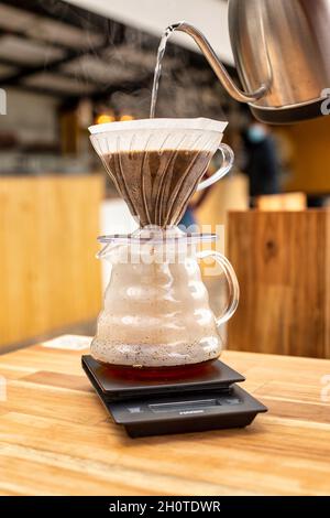 Kaffeebrau. Gießen Sie Wasser über gemahlene Kaffeebohnen in den Filter Stockfoto
