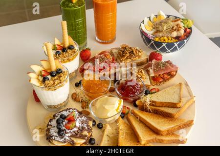 Appetitlich gemischte Bruschettas und Sandwiches in der Nähe der Schale mit Salat und erfrischenden Getränken Stockfoto