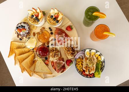 Appetitlich gemischte Bruschettas und Sandwiches in der Nähe der Schale mit Salat und erfrischenden Getränken Stockfoto