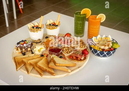 Appetitlich gemischte Bruschettas und Sandwiches in der Nähe der Schale mit Salat und erfrischenden Getränken Stockfoto