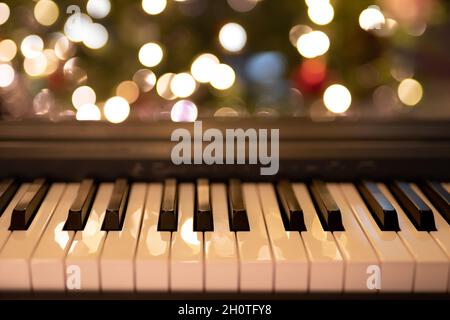 Weihnachtsbeleuchtung und Klaviertastatur. Feiertage, glückliches neues Jahr, Weihnachtskonzept Stockfoto