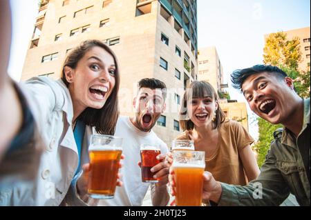 Fröhliche Freunde machen Selfie beim Biertrinken im Freiluftkneipe der Stadt - Freundschafts-Lifestyle-Konzept mit jungem, multikulturellem Jahrtausende-Peop Stockfoto